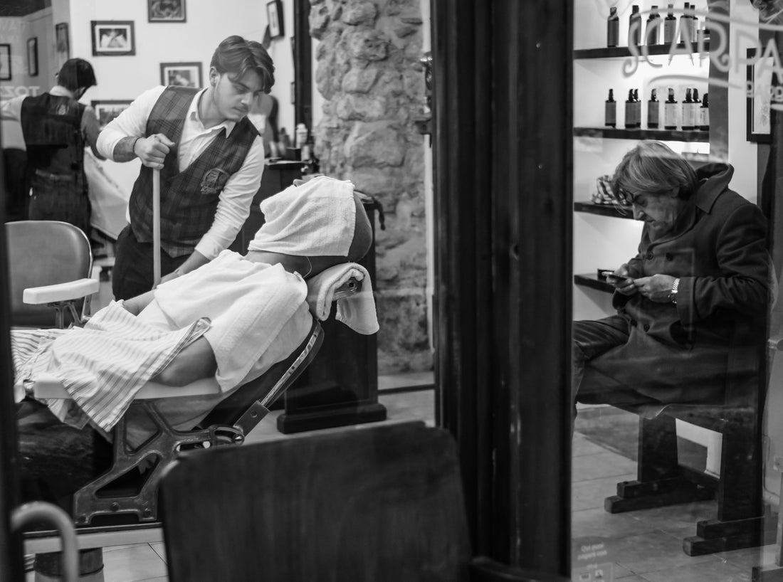 Barber applying warm towel to client's shaved head in a traditional barbershop | Hardwick & Co. post-shave scalp care